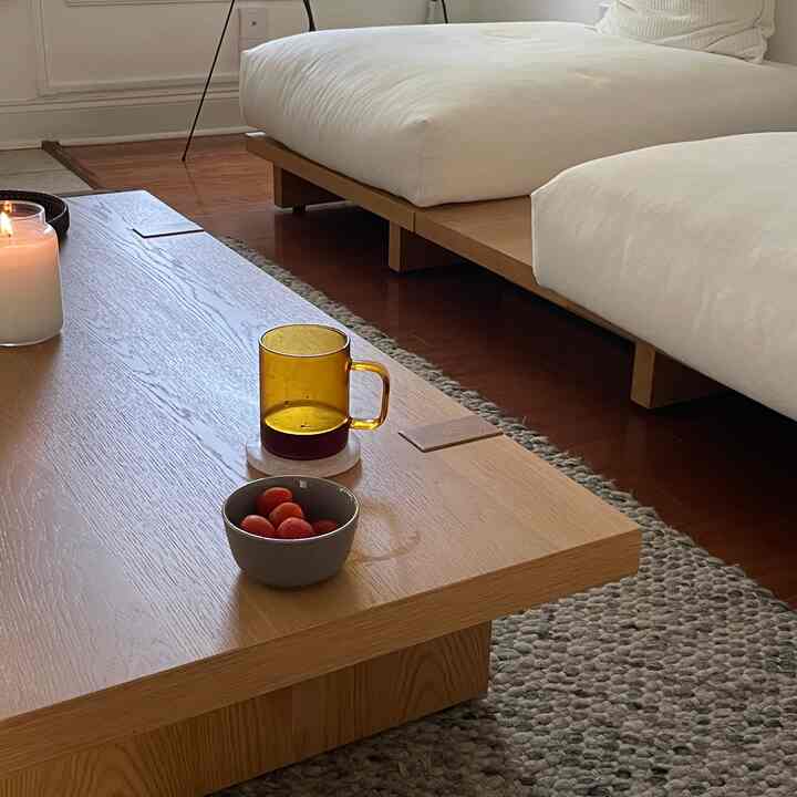 Natural wood-toned minimal Japandi living room featuring low wooden coffee table and white cushioned sofa