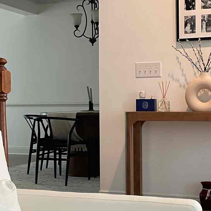 White walls and wood-toned furniture harmonize in a dining room, featuring simple modern style dining chairs for a cozy atmosphere