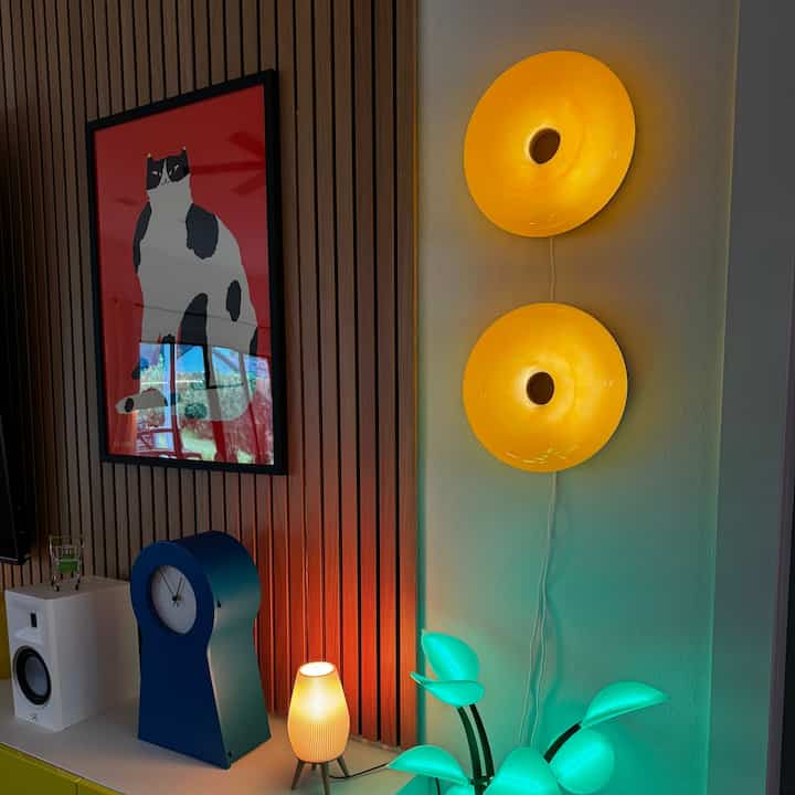 Colorful interior space featuring vivid yellow wall sconces, a blue clock, and a cat poster