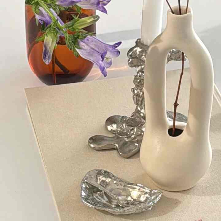 Warm-toned stylish interior decor featuring a silver candle holder and a flower vase