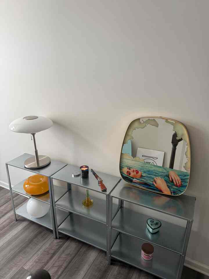 Modern entryway featuring gray metal shelves and white table lamp with minimalist decor