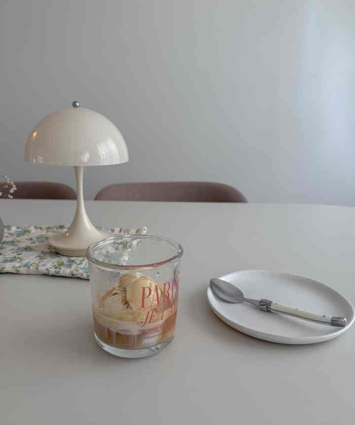 White-toned dining table featuring a table lamp and affogato dessert cup, creating a simple home cafe space