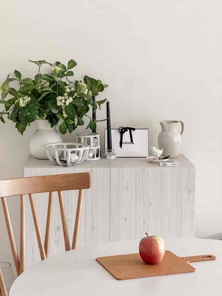 Natural tone and white dining room featuring wooden chairs and plants with a simple interior
