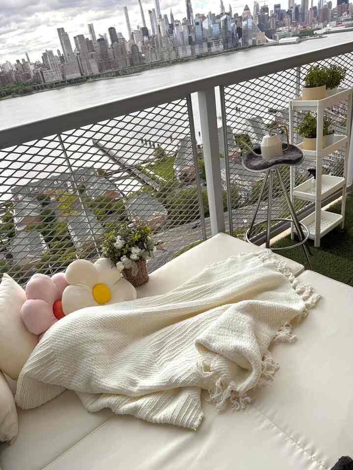 White and beige toned balcony featuring plant shelves and daybed creating a natural relaxing space