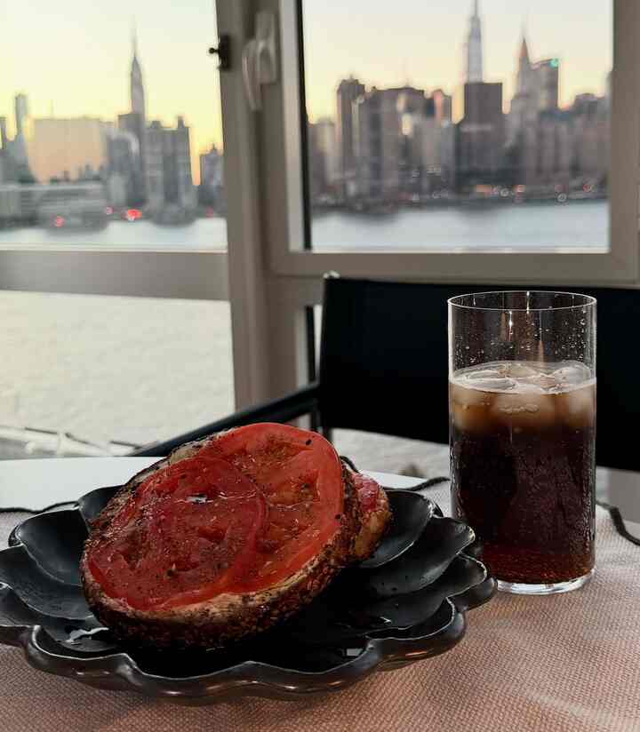 Home cafe scene with black plate and glass set against city skyline visible through window