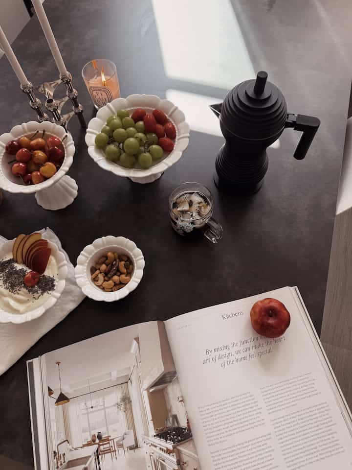 Brown-toned table featuring white bowls, candles, and coffee equipment in a cozy home cafe setting