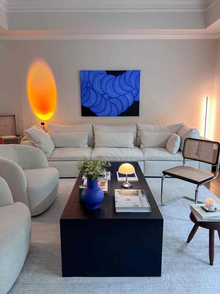 White and black toned living room featuring a sofa, armchairs, coffee table, and table lamp creating cozy ambience