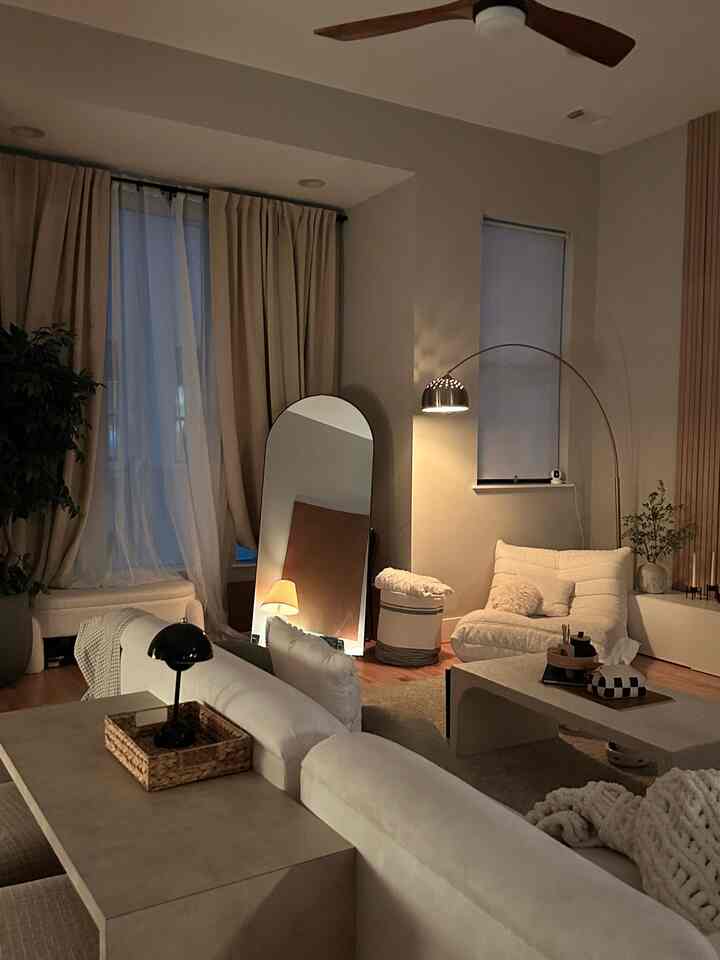 Beige-toned living room featuring an arched mirror and floor lamp with a modern natural and simple atmosphere