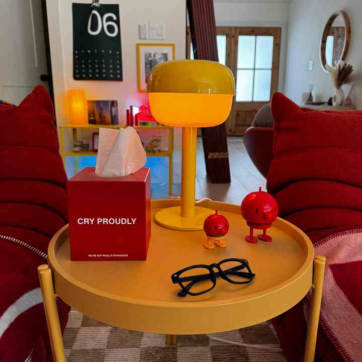 Living room with red cushions and a yellow round table, featuring warm and bright decorative elements