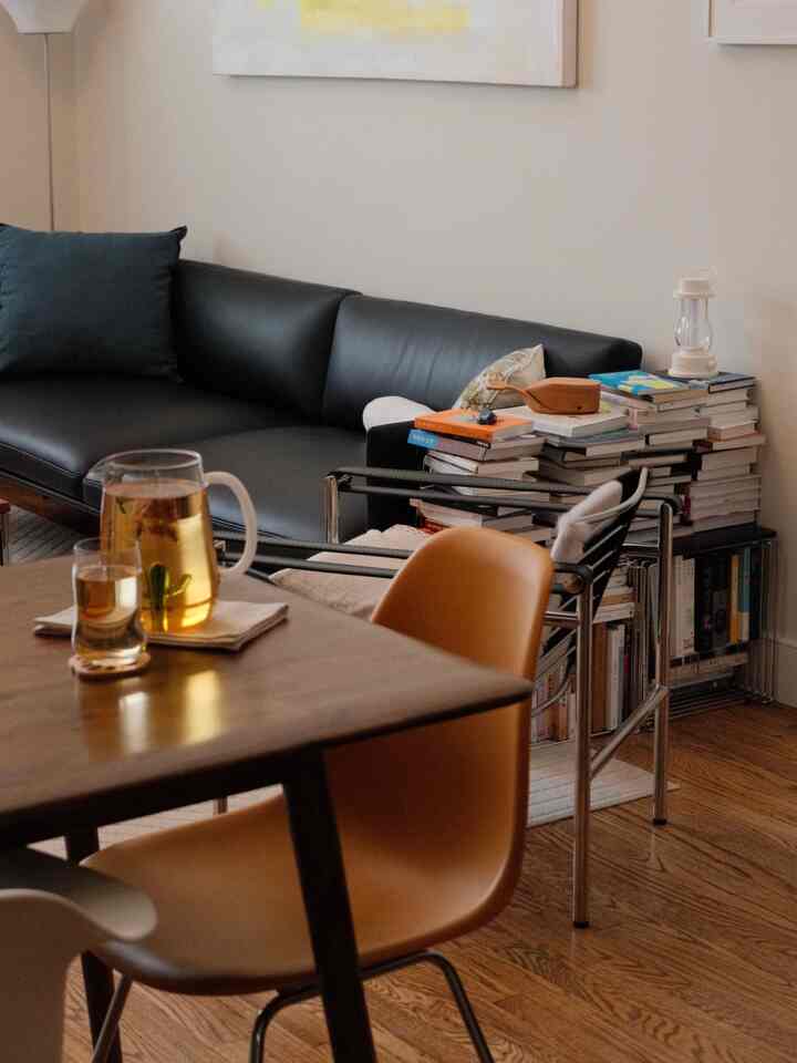 Natural color-toned living and dining room featuring a black leather sofa and wooden dining table with chairs in a cozy setting