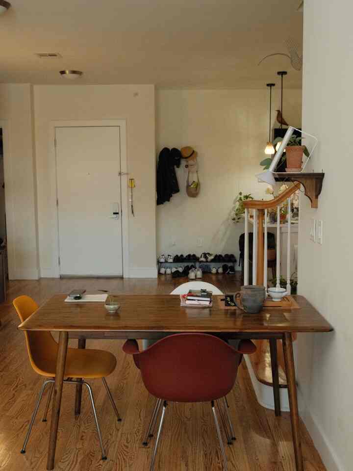 Natural wood tone two-person dining room featuring wooden table and colorful chairs with a cozy entrance area