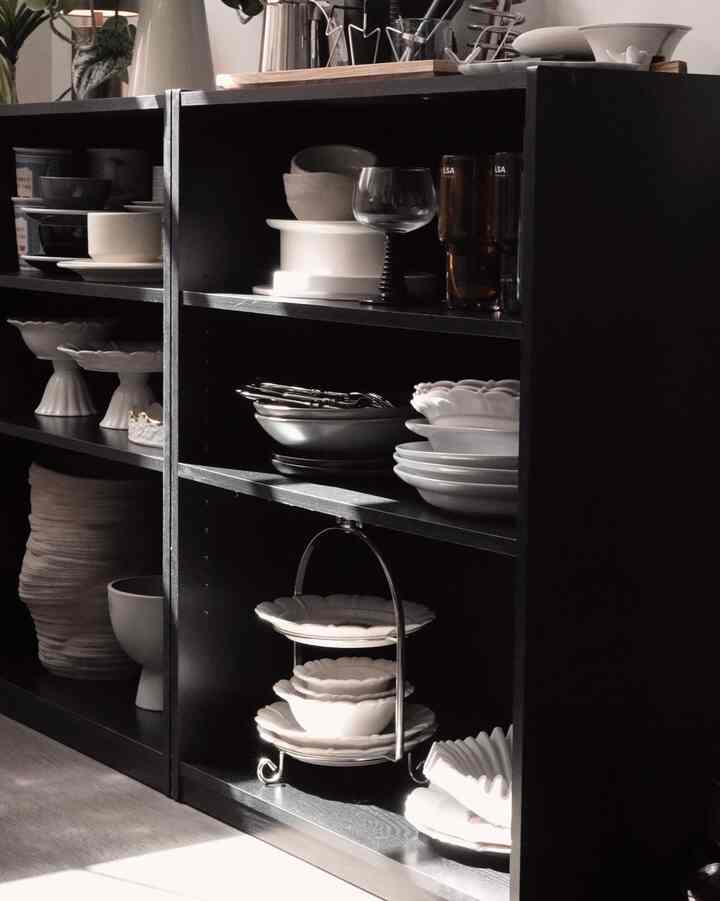 Black shelves neatly organized with white plates and bowls in a kitchen storage space