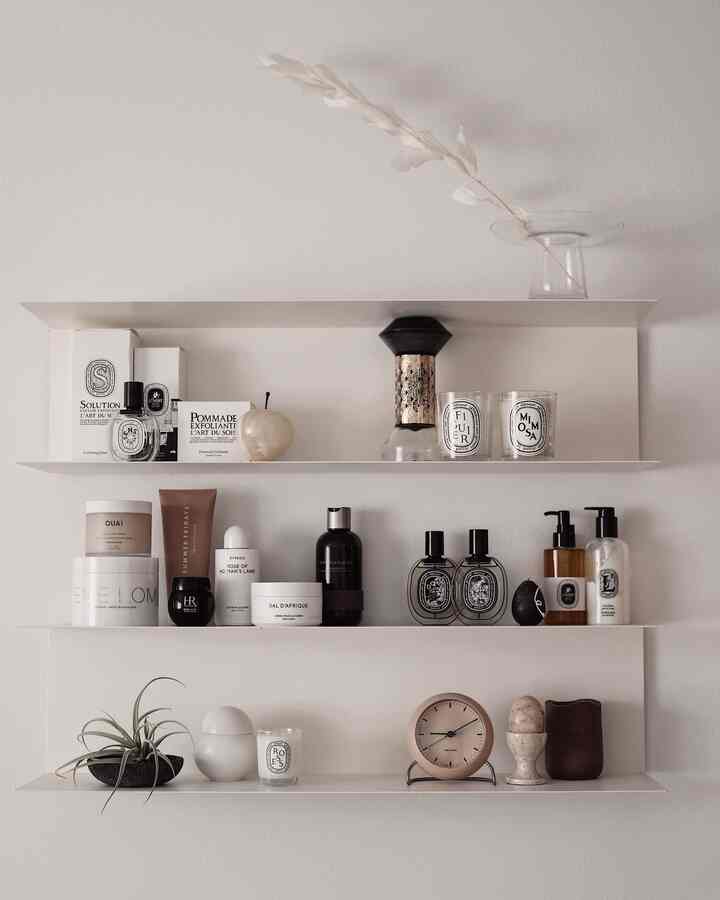 White-toned wall shelves featuring candles, clock, diffusers arranged in a simple modern style interior