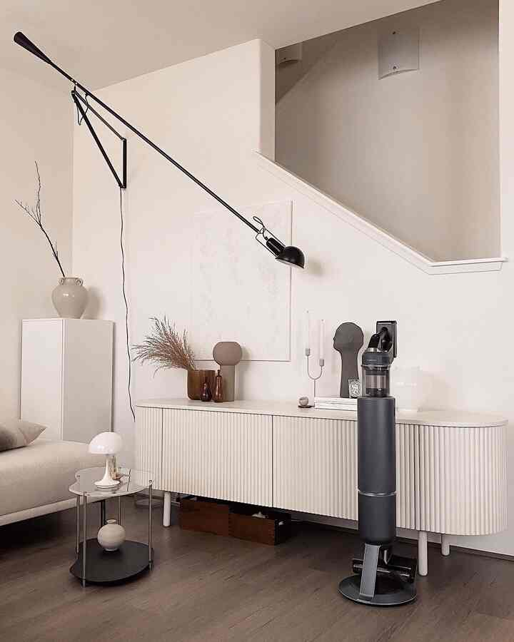 White and brown natural-toned living room featuring a sideboard, coffee table, and wall-mounted lamp with a simple modern atmosphere