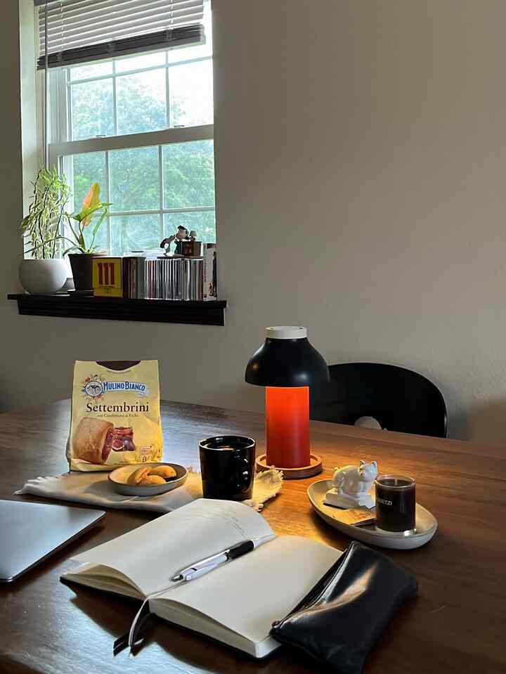 Warm wood-tone dining room featuring black lamp, home cafe items, and remote work essentials on the table creating cozy atmosphere
