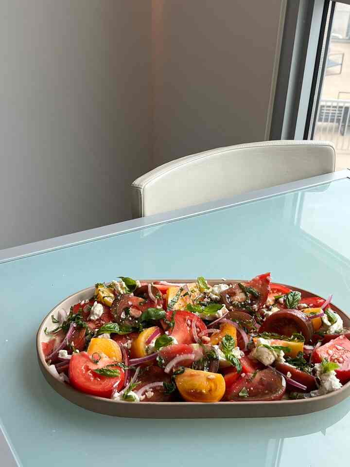 Natural color kitchen space featuring fresh vegetable-filled oval plate on glass dining table with clean atmosphere