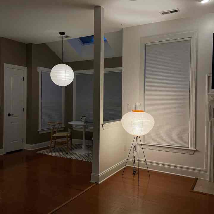 A dining room in white and brown tones featuring rice paper shade pendant and floor lamps, creating a warm natural atmosphere