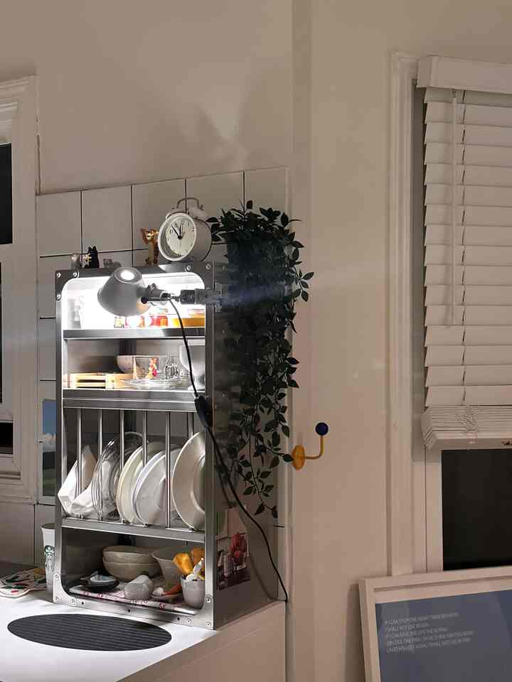 White and green toned kitchen featuring a metal dish storage rack and alarm clock, presenting a simple interior