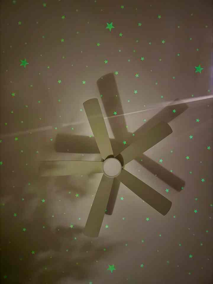 Dark-toned ceiling with a ceiling fan and glowing stars creating a starry effect