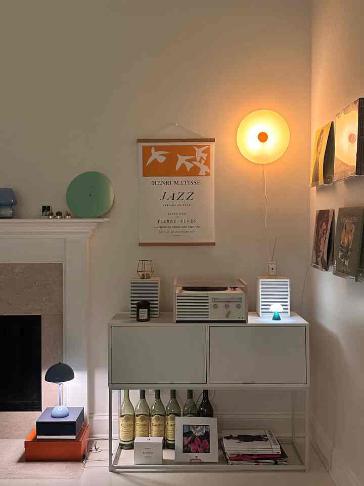 Cozy small living room in warm lighting and white tones, featuring wall-mounted decor poster and multiple lamps