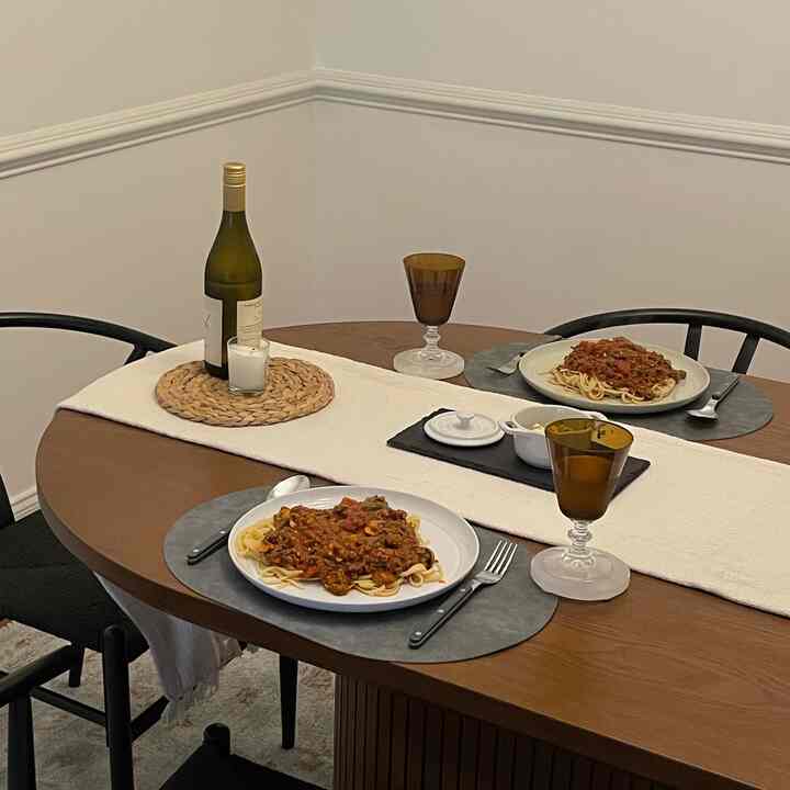 Natural-toned dining room featuring a wooden table set for two with cutlery, wine, and candles, emanating a cozy atmosphere