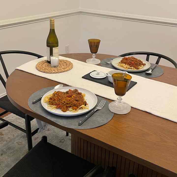 Natural-toned dining room featuring a wooden table with two plates of pasta, creating a simple and cozy atmosphere