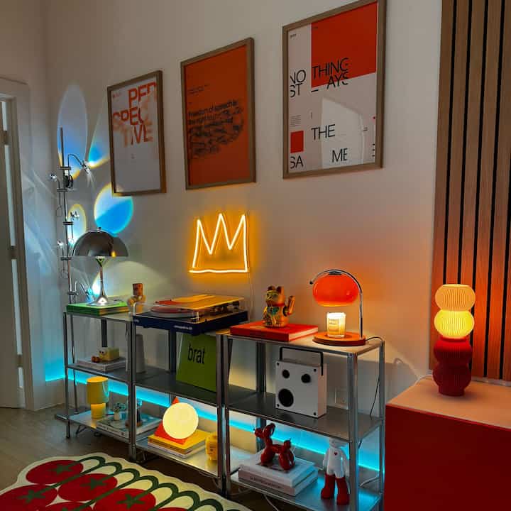 Colorful living room featuring vibrant lighting, posters, and eclectic decorative objects