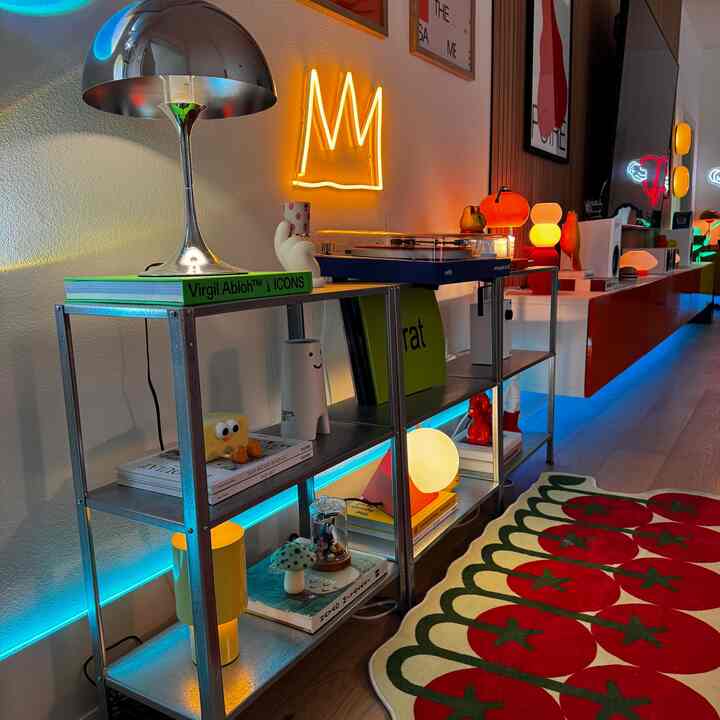 Light brown wooden floor living room with metal shelving, vibrant objets and neon lighting creating a fun, lively atmosphere
