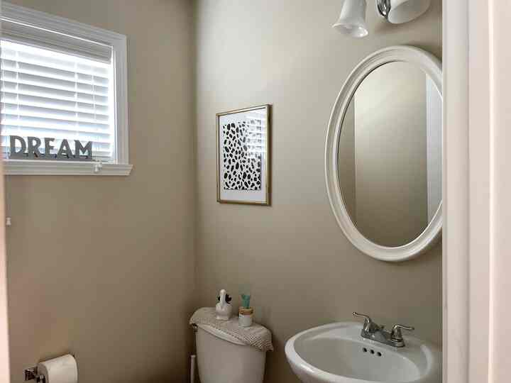 Beige-walled compact bathroom featuring white fixtures and minimal decorative elements