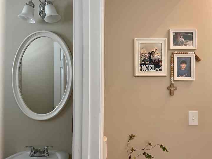 Beige and white toned bathroom featuring white picture frames on wall, simple and cozy atmosphere