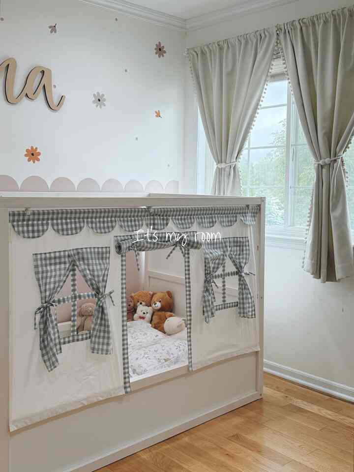 A white and wood tone kids' room featuring a tent bed with stuffed animals, creating a cozy atmosphere