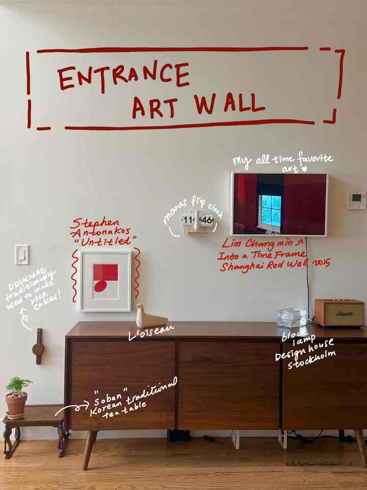 Entrance space with white walls, brown console table, vintage flip clock, and an art wall display