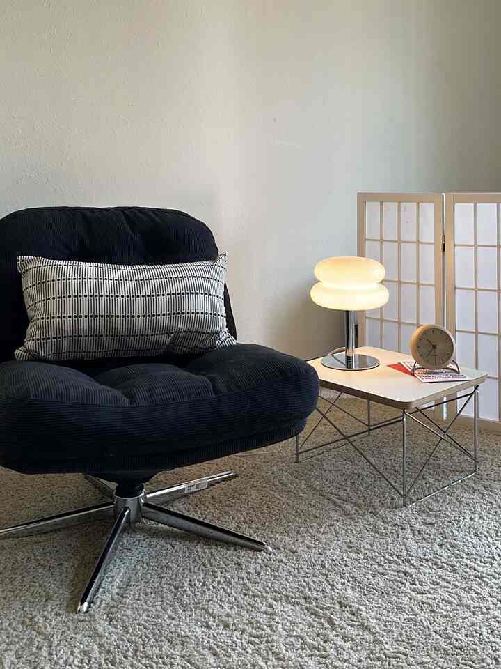 Minimal style space with clean white walls and table, featuring a black armchair