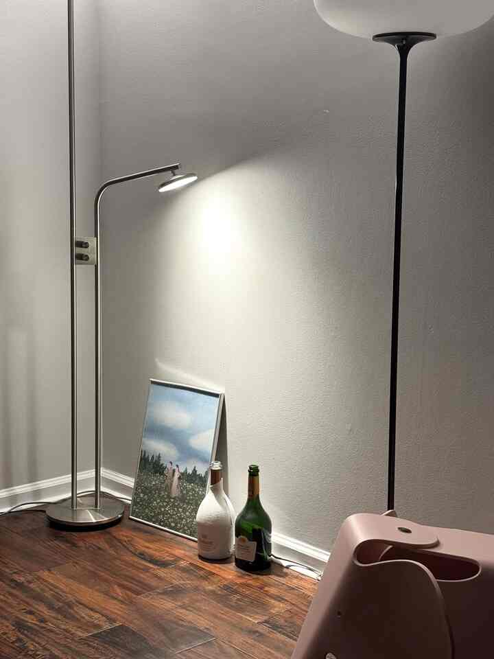 Living room corner with white walls and wood tone flooring, featuring metal floor lamps and soft lighting creating a cozy atmosphere