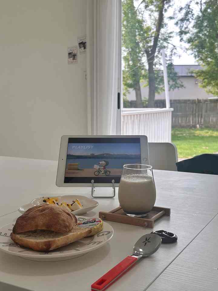 White-toned kitchen table featuring brunch items, glass, and tablet creating a simple and calm atmosphere