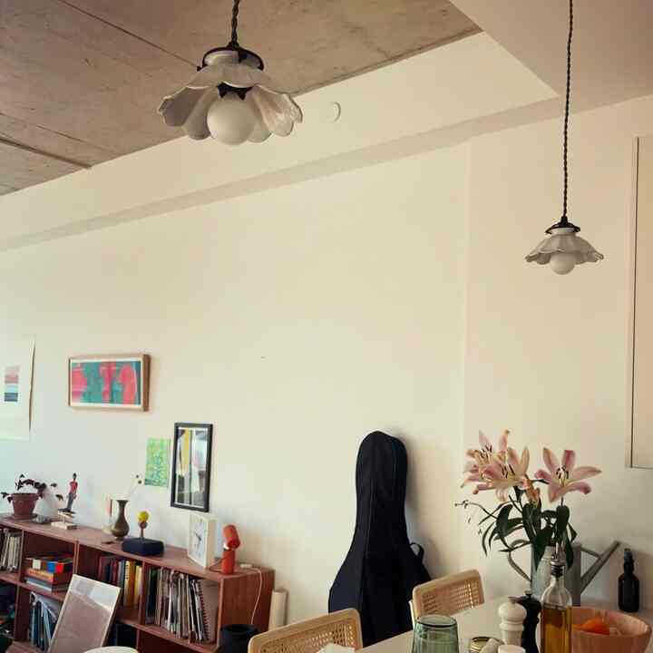 Bright white and wood tone living room featuring pendant lights, shelves, and flower vase creating a simple atmosphere