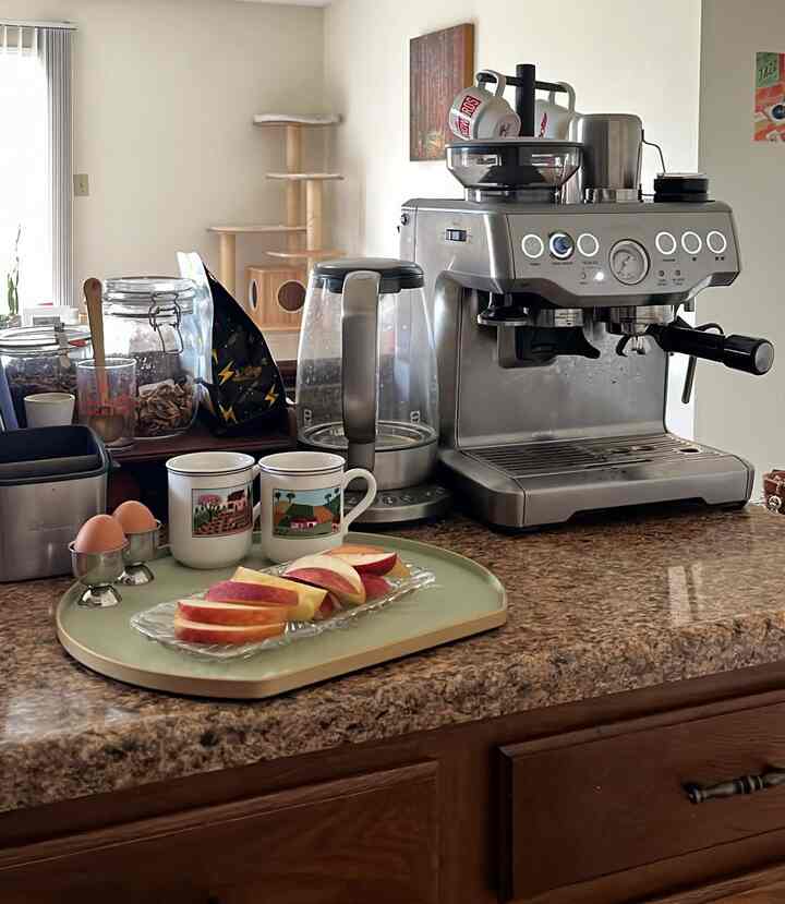 Warm brown and beige toned kitchen counter featuring a coffee machine and design mugs in a cozy home cafe setting