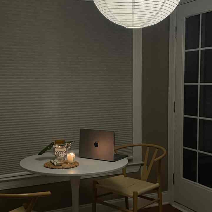 Warm beige walls with a white round dining table in a cozy home office, featuring a laptop and lit candle