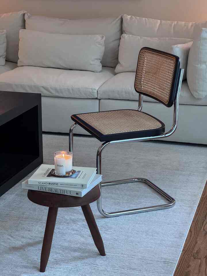 Modern living room featuring a beige sofa and rattan stool, with natural color tones and simple furniture arrangement