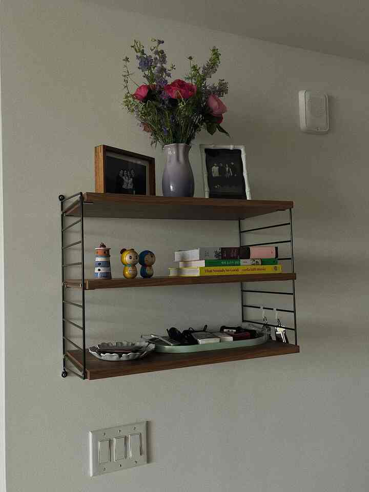 White and wood tone entrance shelf featuring a vase with garden roses, picture frames, creating a cozy atmosphere