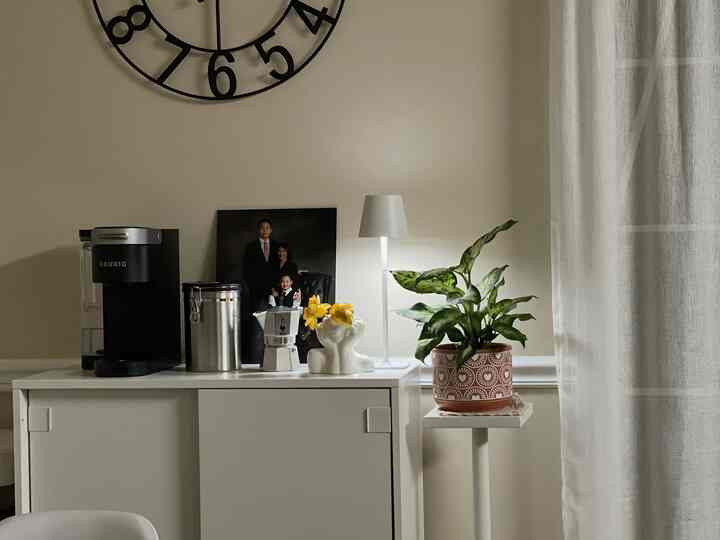 Beige wall and white furniture with table lamp, plant, and coffee appliances in a cozy home cafe area