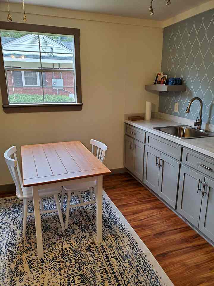 Simple kitchen dining space with wood-tone flooring and white chairs
