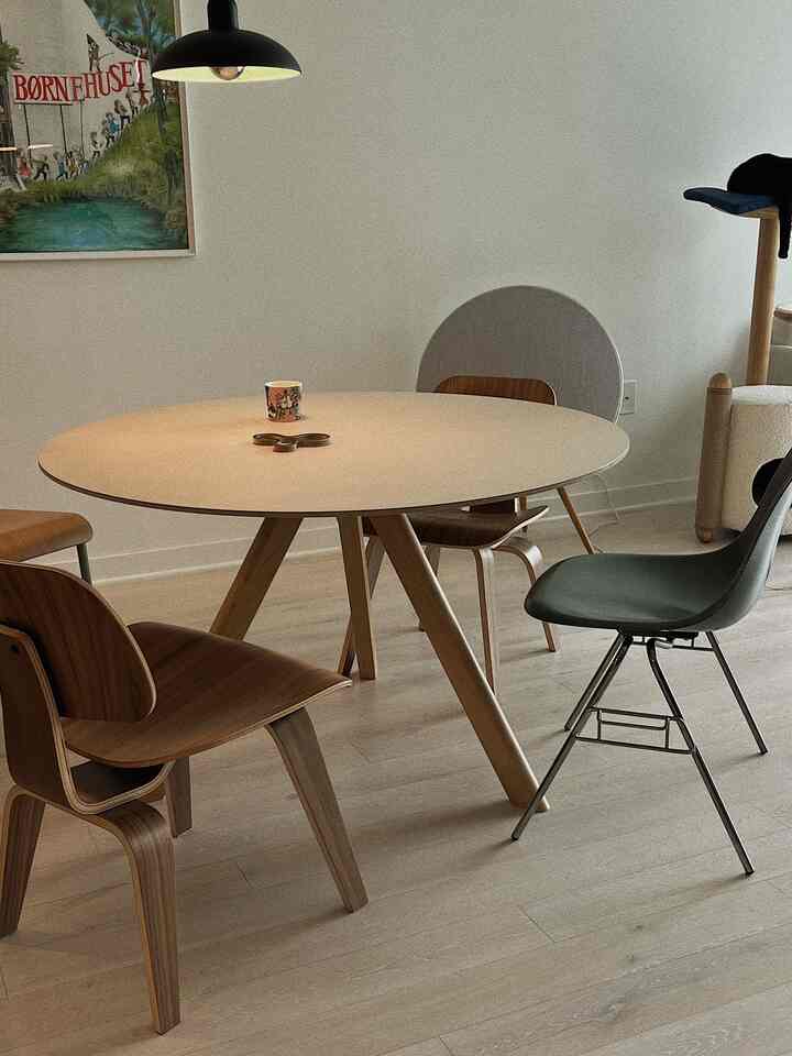 White-walled dining room with wood tone round dining table and chairs, cozy atmosphere
