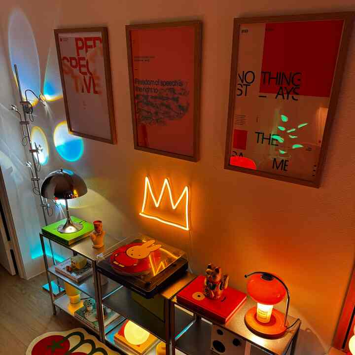 Cozy retro-style interior with orange neon light crown and bold red posters on wall, featuring metal shelving with turntable and decorative items