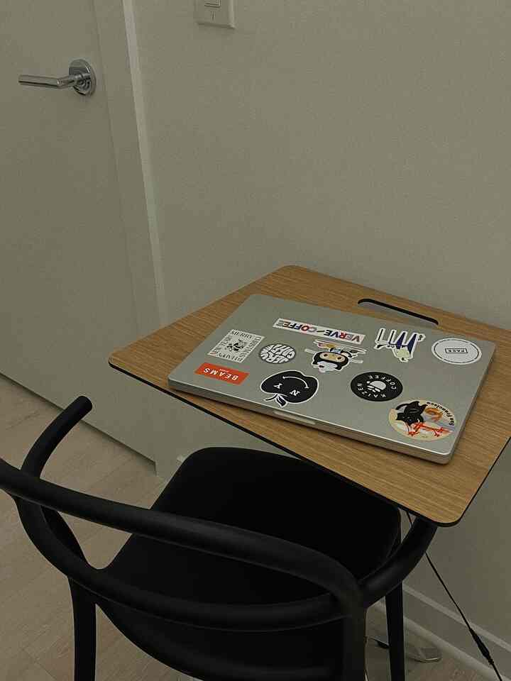 Natural color studio apartment featuring a wood desk with laptop and a black office chair in a modern home office setup for remote work