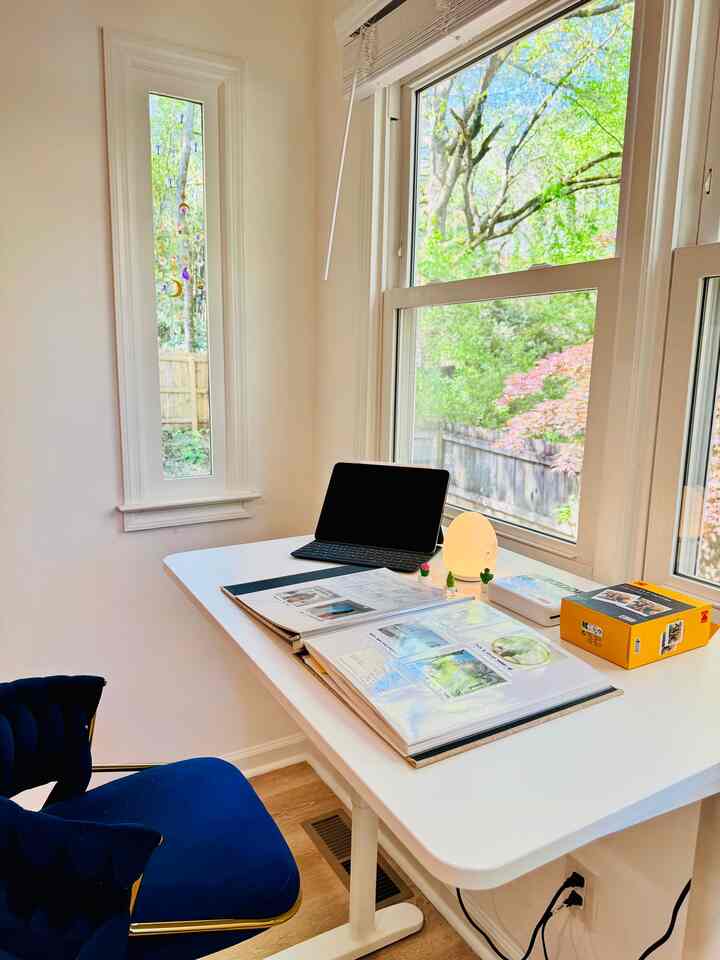Bright white-toned home office with a desk by the window and a blue chair, creating a modern and cozy workspace