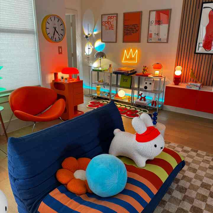 A colorful living room featuring red and blue tones, a vibrant sofa with a plush rabbit toy, creating a trendy atmosphere