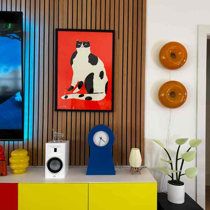 White and yellow toned living room featuring a cat artwork, blue clock, wall sconces, and wood paneling for a modern interior