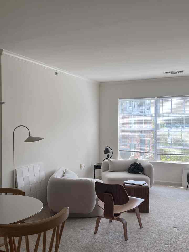 Beige and wood-toned living room featuring cream armchairs and wooden chairs, arranged in a minimal and natural styled space