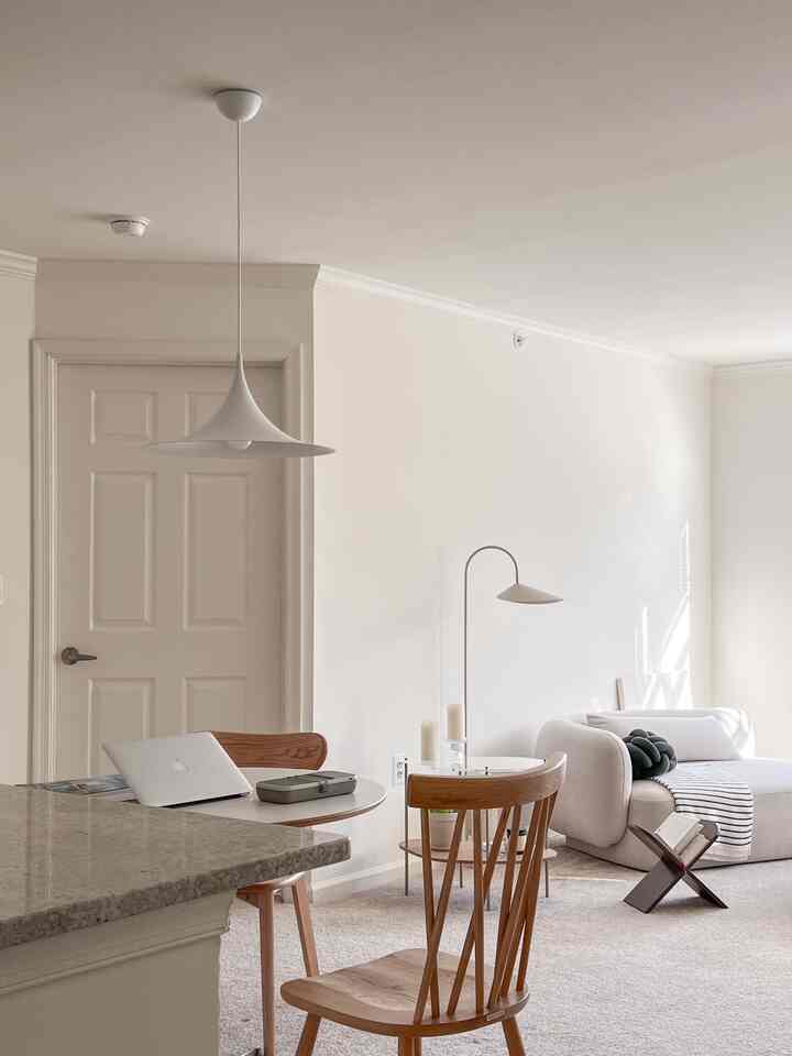 Beige-toned studio apartment living and kitchen area featuring natural wood furniture, modular sofa, and pendant lighting creating a cozy ambiance